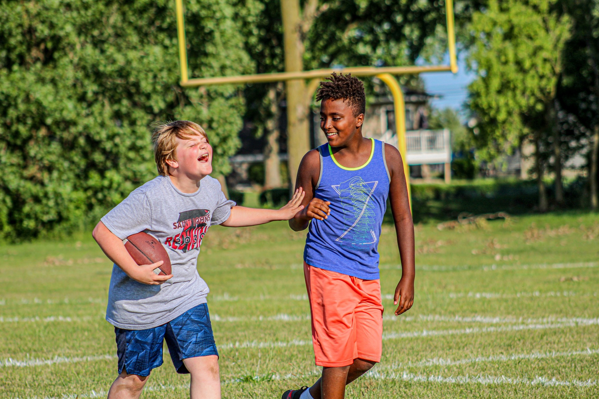 Two teens playing touch football and laughing