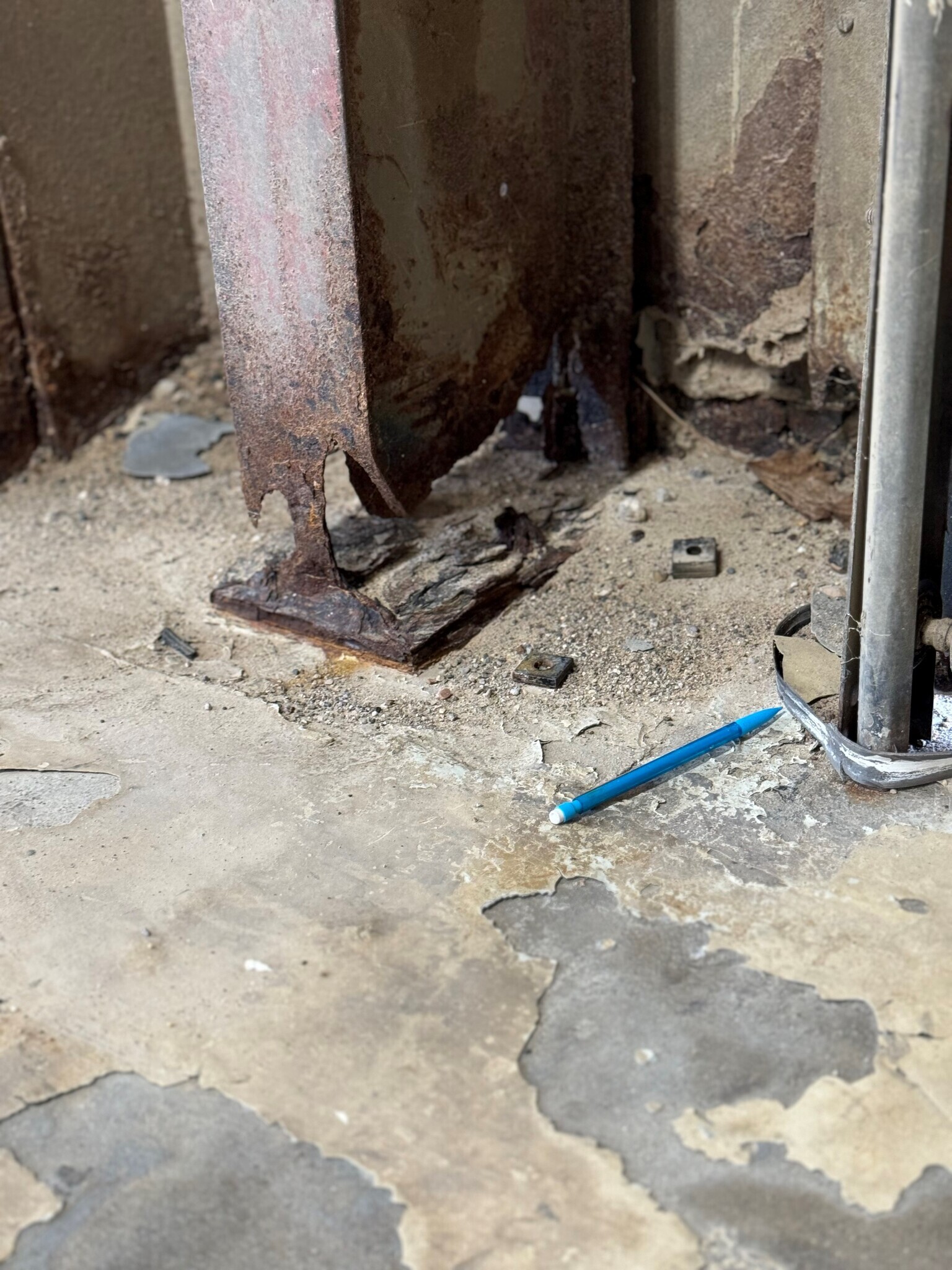 Photo of deteriorating metal beam within aging bus garage